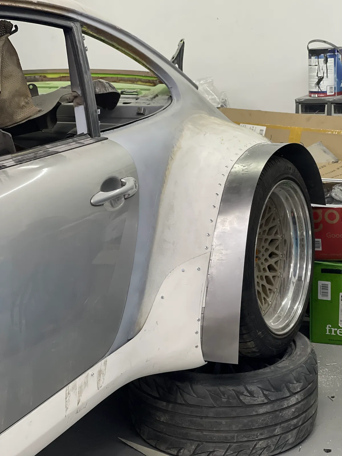 A hand-fabricated steel arch being fitted and riveted to the Porsche 911