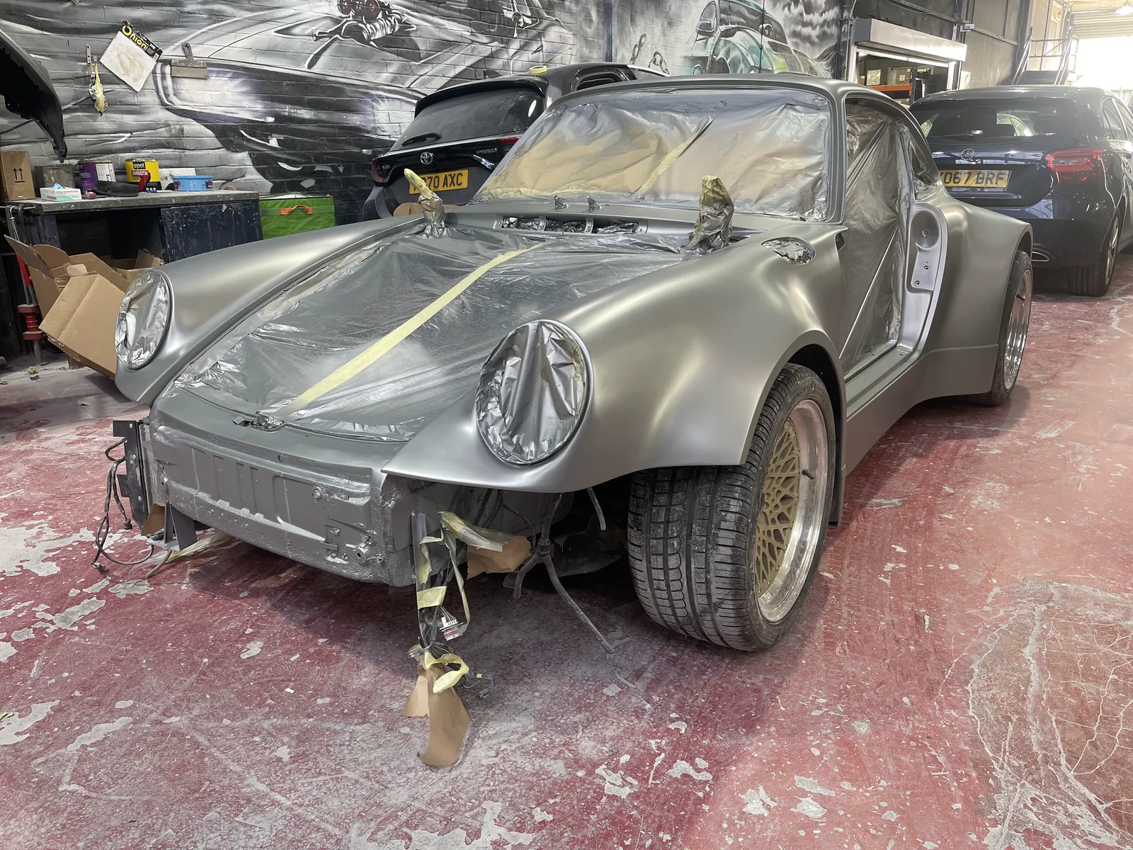 The Porsche 911 with base coat applied, still masked in the workshop